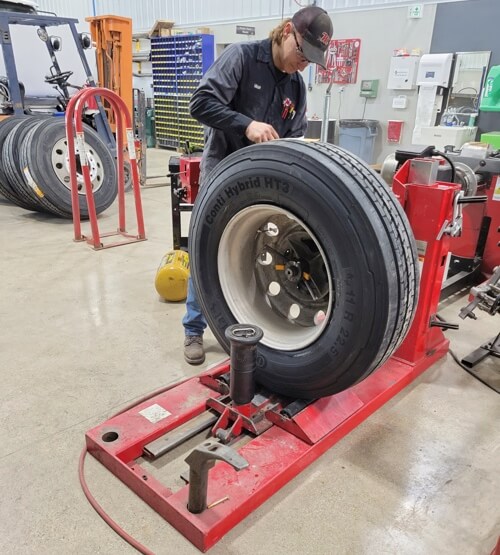 Key Signs You Need a New Set of Tires in Etna Green IN with Mast Service Center image of technician checking big rig tire in shop