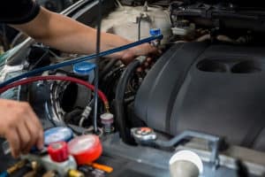 Where to Go When Your Car AC Stop Working in Etna Green, IN | Mast Service Center, Inc. Image of an auto mechanic checking and fixing a car’s air conditioner system in a car garage.