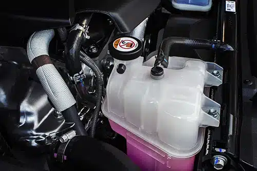 Checking & Topping Off Your Coolant For Winter: Is It Important? | Mast Service Center in Etna Green, IN. Closeup image of a coolant tank with a pink liquid antifreeze of a radiator system in car.