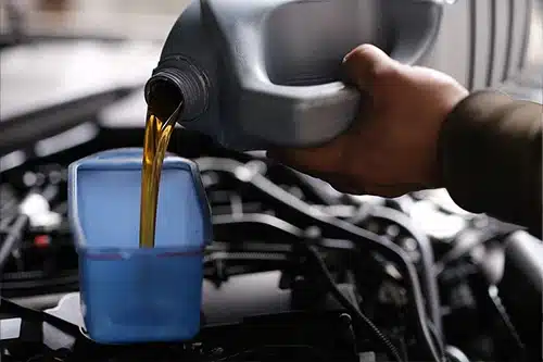 5 Simple But Common Light-Duty Truck Problems (and How to Avoid Them) | Mast Service Center in Etna Green, IN. Closeup image of an auto mechanic pouring oil for replacement into an engine.