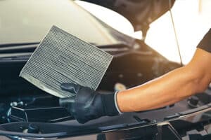 Hand of a mechanic holding dirty cabin air filter old. Concept image of “7 Simple Tips to Preventive More Expensive Auto AC Repairs” | Mast Service Center in Etna Green and Nappanee, IN.