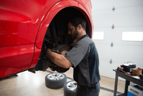 Brake repair services near me in Etna Green, In at Mast Service Center. Image of mechanic servicing brakes on red vehicle in shop.