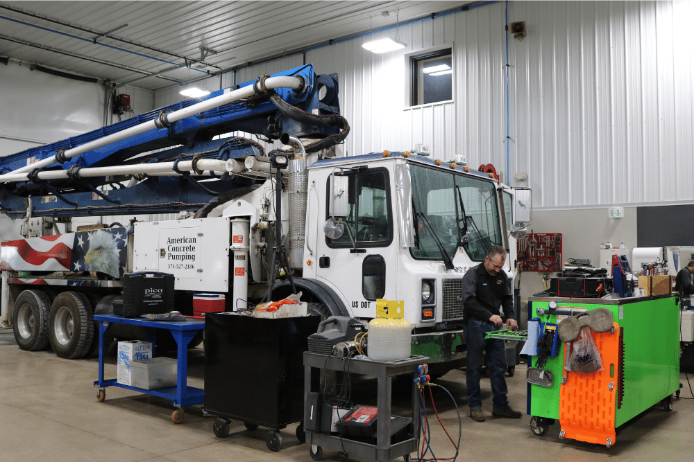 Fleet Inspection Checklist in Nappanee, IN at Mast Service Center. Mechanic inspecting a car engine and writing notes on a clipboard during a vehicle maintenance check.