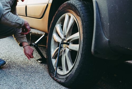 A roadside assistance technician fixes a flat tire on a truck.